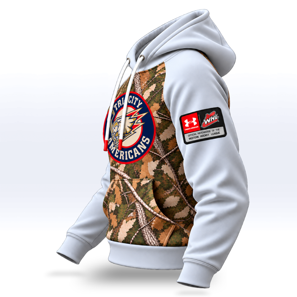 A white pullover hoodie with a large front graphic featuring a woodland camouflage pattern and a circular Tri-City Americans logo. A red and white Under Armour patch is printed on the right sleeve.